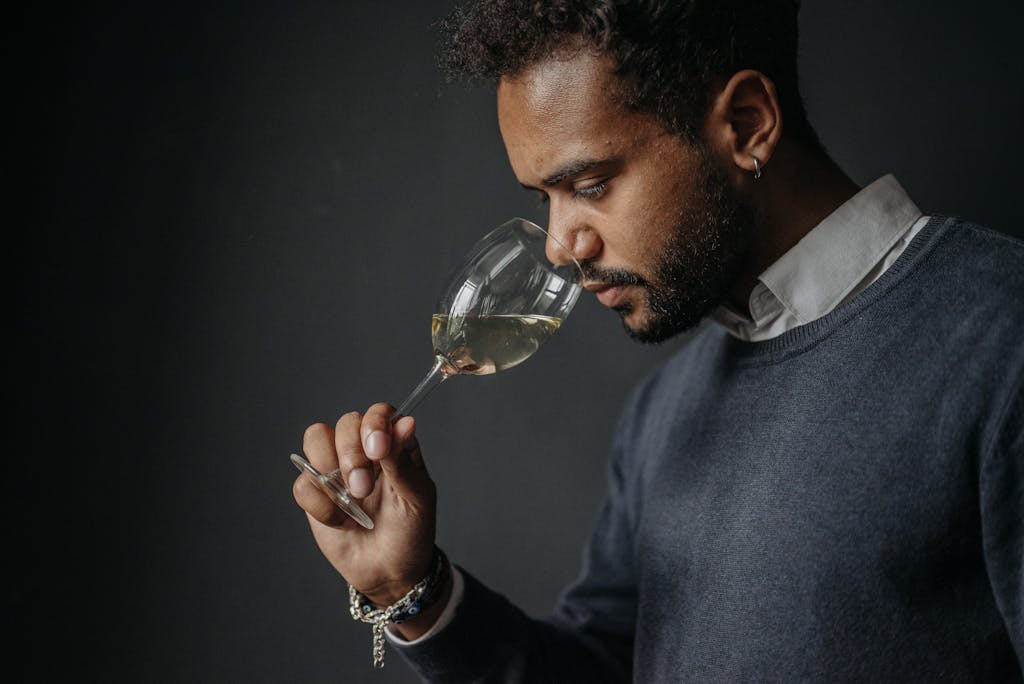 Side profile of a man appreciating white wine aroma in a studio setting. Captures a moment of sensory experience.