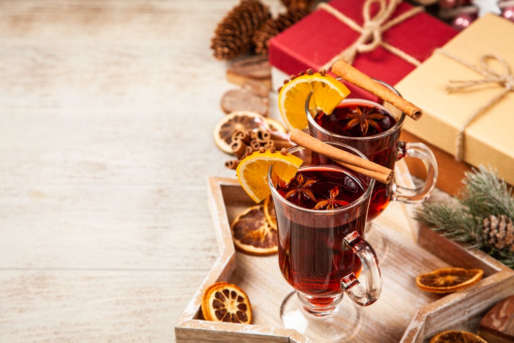 A cozy setup featuring mulled wine with cinnamon and orange slices, perfect for the holiday season.