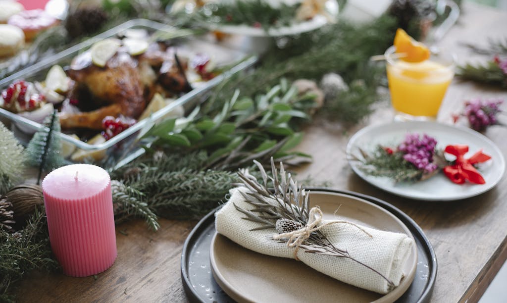 High angle of table served for Christmas dinner with plates with napkins and traditional roasted turkey on glass dish decorated with fir twigs